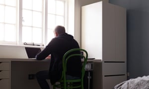 Teenage boy sitting at desk in bedroom using laptop