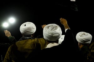 Back view of heads in turbans and raised fists at night
