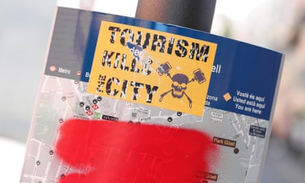 A sticker that reads: ‘Tourism kills the city’ seen on a damaged tourist map near Park Güell.