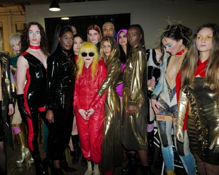 Pam Hogg surrounded by women in shiny fashion outfits.