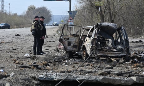 Policemen examine a destroyed car after missiles strike in Kharkiv, on April 6, 2024.