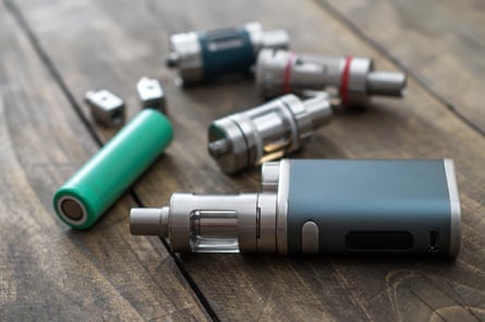 Various part of a vape device and a battery sit on a table
