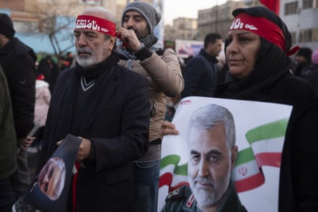A mourner at the funeral in January 2020 of Qassem Soleimani carries a poster showing his face