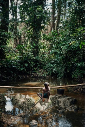 Child sits on a rock in a stream