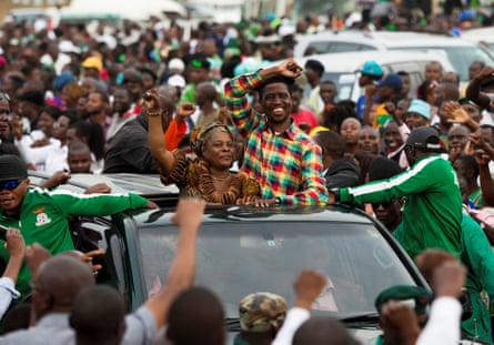 Edgar Lungu and his wife wave to crowds from an open-top vehicle.