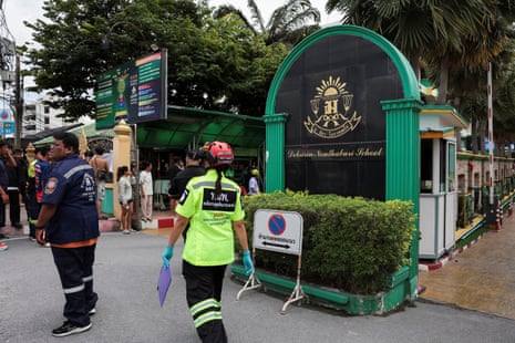 People, including emergency personnel, gather outside the prestigious Debsirin Nonthaburi School.