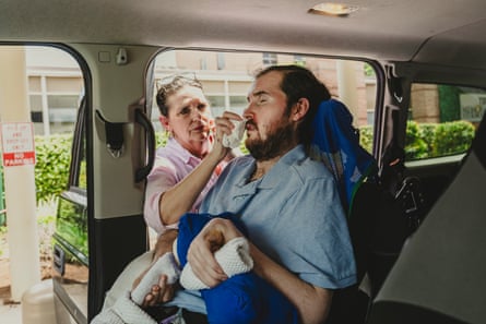 A woman dabs sweat of her sons face who is sitting in a car