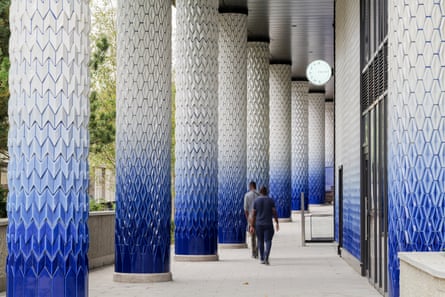 two men walking down a colonnade of tiles going from dark blue to white