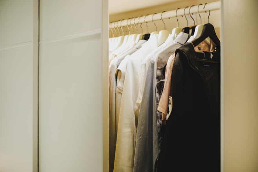 A closet with work clothes hanging in it