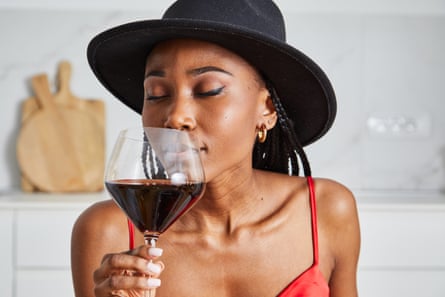 Posed by model.  Young adult black woman enjoying red wine in home kitchen