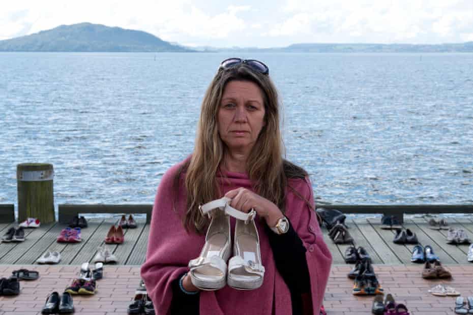 Suzy Taylor holds a pair of her daughter Georgia MacBeath’s sandals in front of the shoes of other New Zealand suicide victims on the lakefront at Rotorua