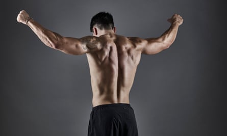A muscular shirtless man shown is shown from behind.