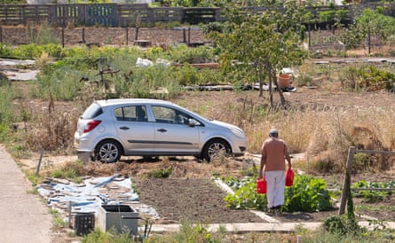 A man waters an allotment in Slough, Berkshire, using water cans on another hot day.