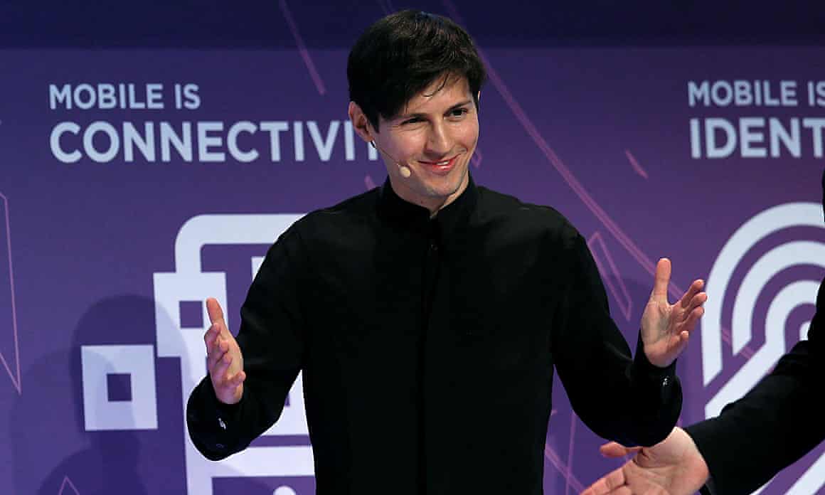 Pavel Durov, wearing a black shirt and headphone microphone, stands smiling with his hands outstretched.