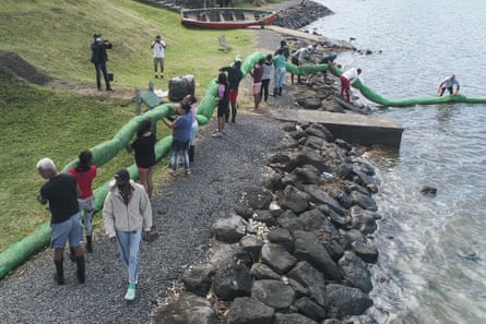 A group of people carry homemade booms on their shoulders on a rocky shore