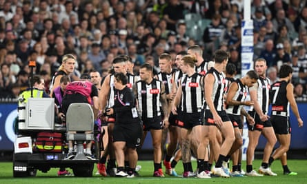 Los jugadores de Collingwood observan cómo Jeremy Howe sale del campo.