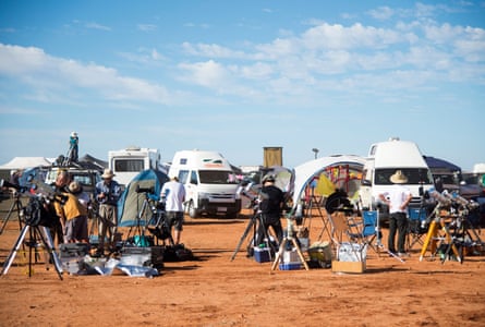 A view of telescopes and campervans set up on red dirt