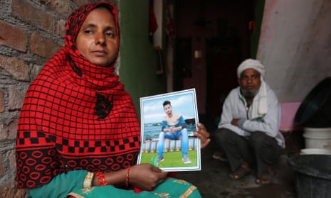 Fatima Begum, sitting in front of her husband, at her house in Kasganj, Uttar Pradesh, showing the photo of her son Altaf