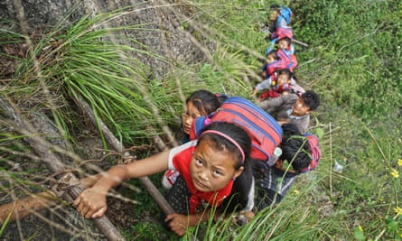Children of Atule’er Village climb the vine ladder on a cliff on their way home in Zhaojue county.
