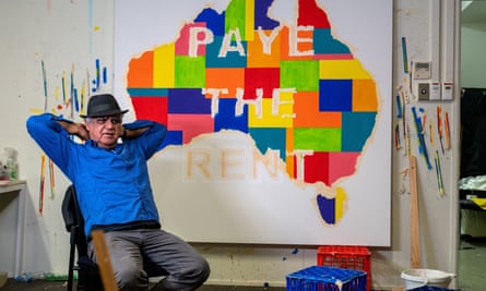 Richard Bell with a multicoloured map of Australia that says 'Paye the rent'