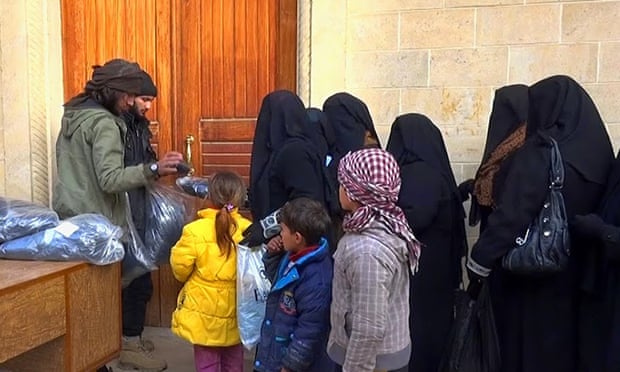 In this photo released by a militant website, members of Islamic State group distribute niqabs to women in Mosul.