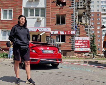 Woman with damaged car in front of apartment block