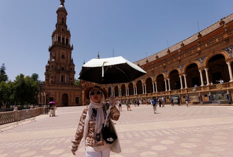 A woman shelters from the sun with a parasol, scarf and sunglassses on June 21, 2026 in Seville, Spain. Western Europe is facing its second major heatwave of 2026, driven by a high-pressure system known as a “heat dome” that is drawing hot air from North Africa across the region.