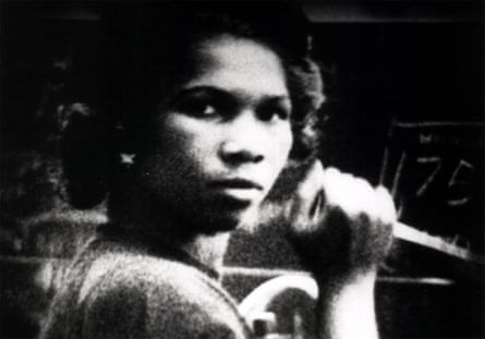 A woman looking directly at the camera, holding a microphone.