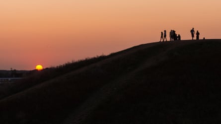 People watch the sun setting at Northala Fields in Northolt, north-west London, on the last evening before the autumnal equinox, which marks the end of summer and the beginning of autumn.