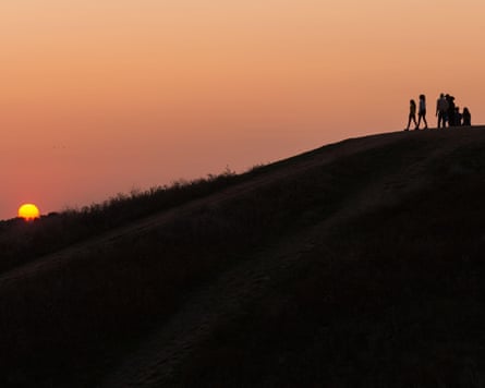 People watch the sun setting at Northala Fields in Northolt, north-west London, on the last evening before the autumnal equinox, which marks the end of summer and the beginning of autumn.