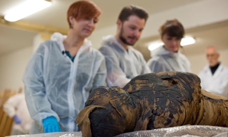 The Warsaw Mummy Project team looking at the bandaged mummy