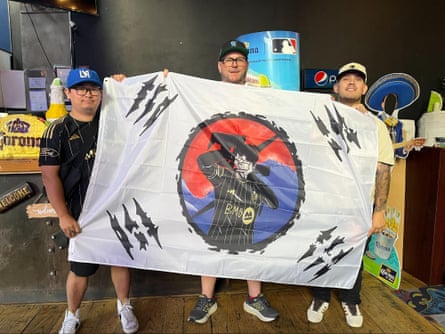 Daniel Cho, the designer of the Son-inspired flag, stands next to Sam Seig and Angel Salgueroi at a Los Angeles Football Club watchparty in Koreatown on August 16, 2025.