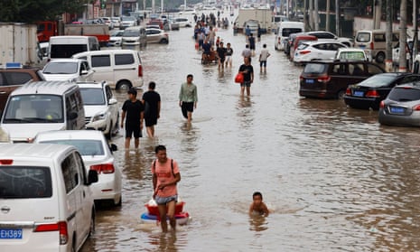 People wade through flood waters following heavy rainfall in Zhengzhou, China