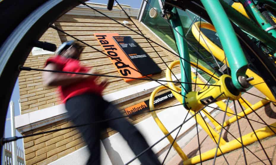 a picture of a cyclist leaving a Halfords store taken through the spokes of his bike