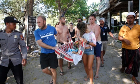 Foreigners on Gili Trawangan carry an Indonesian woman injured in the earthquake