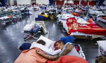A couple sleeps on cots at the George R Brown Convention Center, where nearly 10,000 people are taking shelter.
