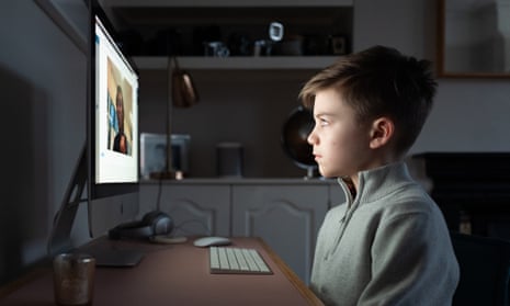 A schoolboy watching an online lesson from his teacher