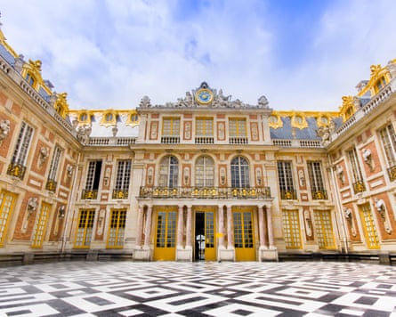 Opulent gold and white facade of Palace of Versailles seen from its marble courtyard