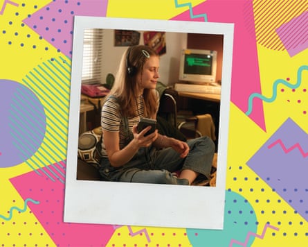 An old photo of a teenage girl sitting in a room in front of a basic computer, wearing headphones and listening to a portable cassette player