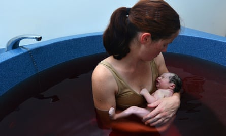 Woman holds her baby in a pool after natural water birth.E3P867 Woman holds her baby in a pool after natural water birth.