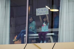 A girl holds up a sign at a hotel window overlooking the Cop26 venue