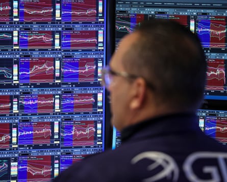 A stock market trader looks at prices on a screen.