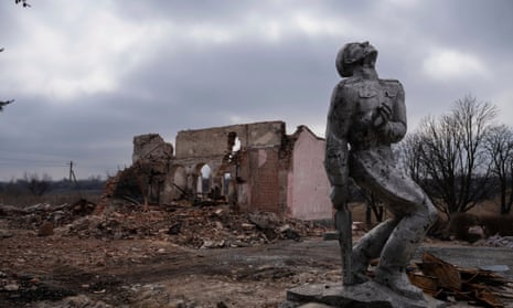 A Soviet-era monument dedicated to the servicemen of the second world war stands in front of a destroyed house near Avdiivka.