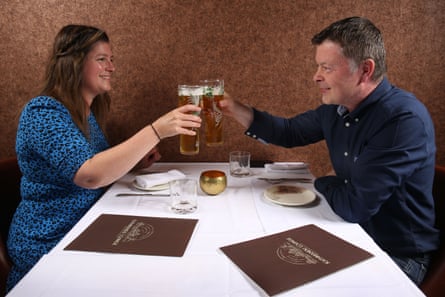 Nyree and Karl saying cheers with their pints across a restaurant table