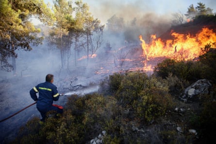 Strażak próbuje ugasić ogromny pożar w wiosce Asklepiou na wyspie Rodos.