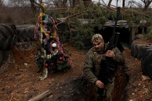Ukrainian serviceman with the Dnipro-1 Special Tasks Patrol Police regiment Raphael Karapitian, 45, walks beside a decorated Christmas tree in the trenches at the frontline on Christmas Eve in Bakhmut