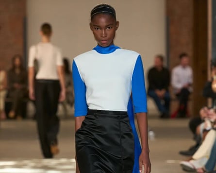 Model wearing a black skirt and white and blue top with a minimalist design