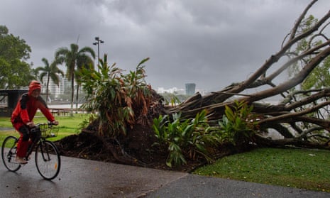 A man cycles past a downed tree as inclement weather from Cyclone Jasper impacts Cairns in far north Queensland on December 13, 2023.