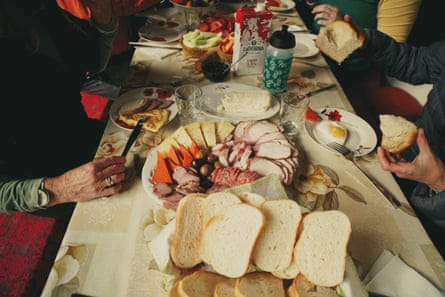 A table with meats, cheeses, bread and vegetables, with the hands of dinners just seen