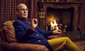 Tom Hollander as Truman Capote, seated beside an open fire